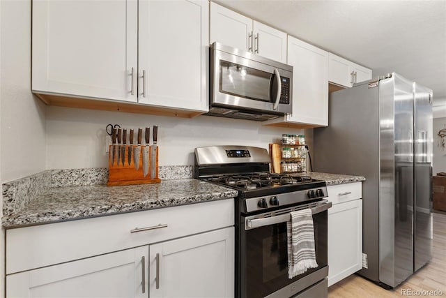 2954 E 101st Ave, Thornton, CO 80229 - kitchen with stainless steel appliances, white cabinetry, light wood-style floors, and light stone countertops