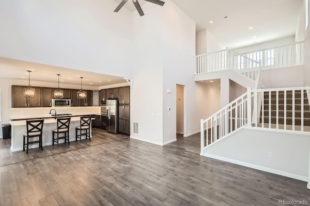 living room with visible vents, a ceiling fan, a high ceiling, and stairway