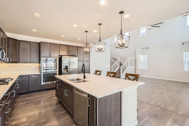 kitchen with appliances with stainless steel finishes, a sink, light countertops, recessed lighting, and dark wood-style floors