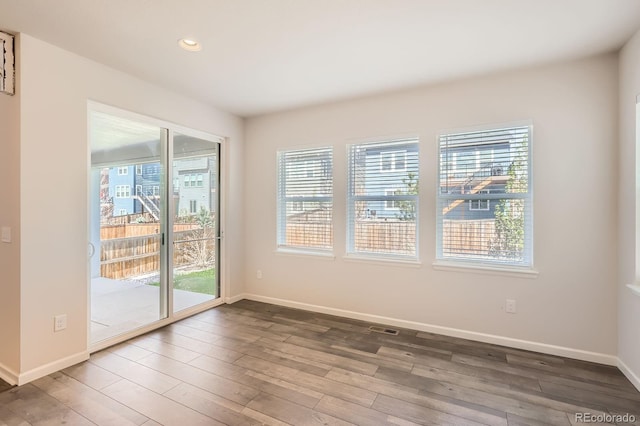 empty room featuring baseboards, plenty of natural light, and wood finished floors