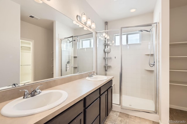 full bathroom with visible vents, a shower stall, a sink, and a spacious closet