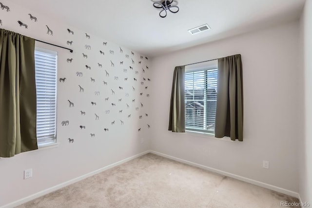 carpeted empty room featuring baseboards and visible vents