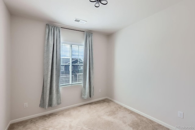 spare room featuring light colored carpet, baseboards, and visible vents