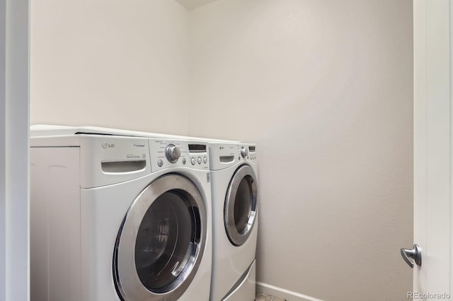 clothes washing area featuring laundry area, baseboards, and washing machine and clothes dryer
