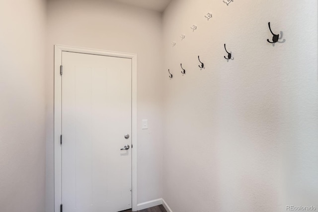 doorway to outside featuring baseboards and dark wood-type flooring