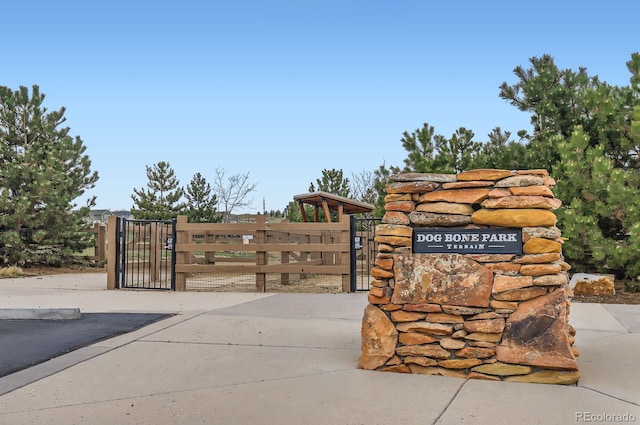 community / neighborhood sign featuring fence and a gate