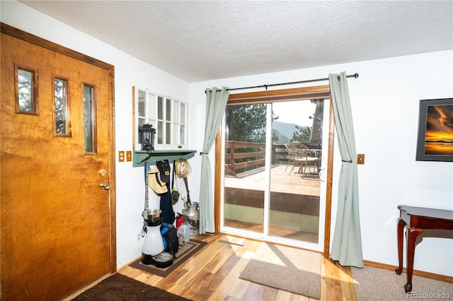 doorway to outside with a textured ceiling and light hardwood / wood-style flooring