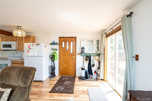 kitchen with white appliances, light hardwood / wood-style flooring, and a textured ceiling