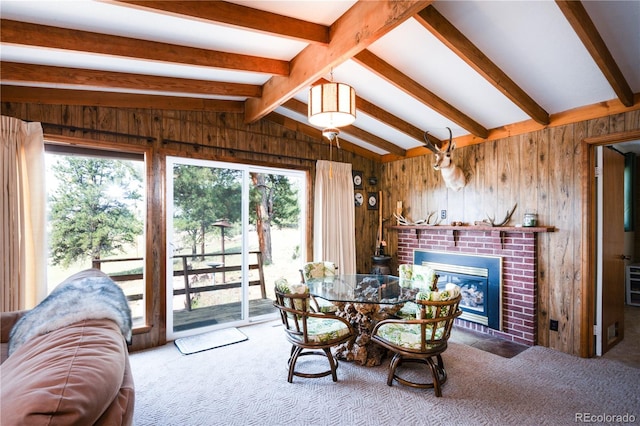 carpeted dining area featuring lofted ceiling with beams, a brick fireplace, and wood walls