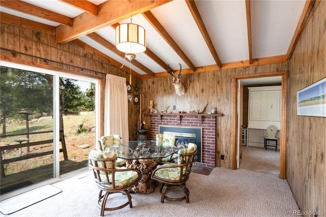 dining space featuring wood walls, a brick fireplace, light carpet, and vaulted ceiling with beams