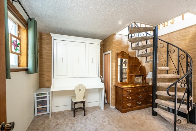 interior space featuring light colored carpet, a textured ceiling, and wood walls