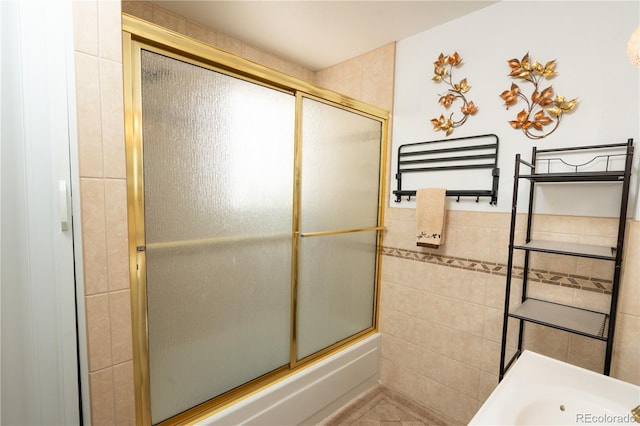 bathroom featuring shower / bath combination with glass door and tile walls