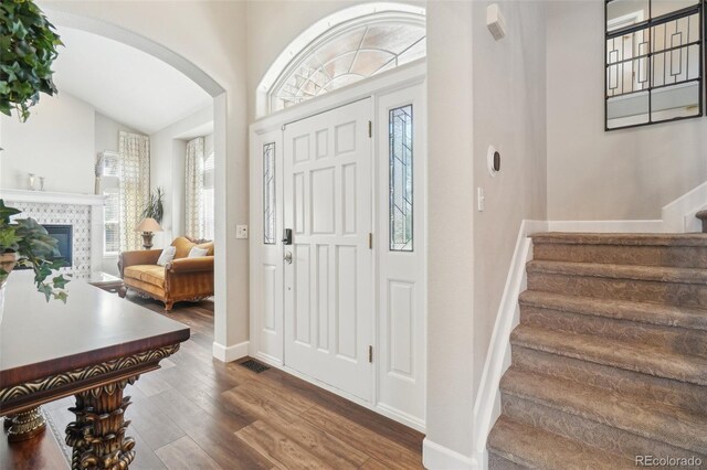 entryway featuring visible vents, arched walkways, wood finished floors, stairway, and baseboards