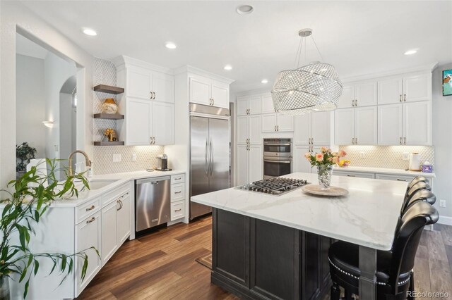kitchen with open shelves, appliances with stainless steel finishes, decorative backsplash, and a sink