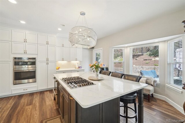 kitchen featuring dark wood-style flooring, a kitchen breakfast bar, white cabinets, and stainless steel appliances