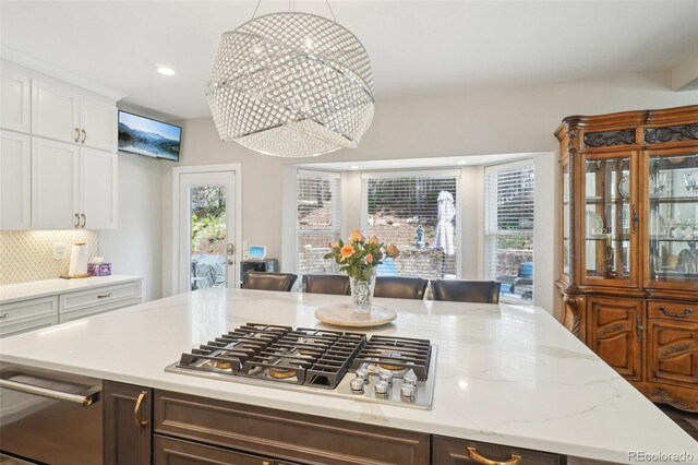 kitchen with decorative backsplash, stainless steel gas cooktop, light stone countertops, white cabinets, and recessed lighting