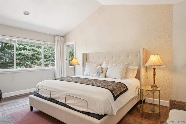 bedroom with baseboards, lofted ceiling, and wood finished floors