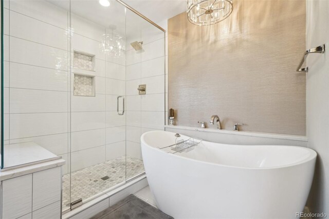 full bath with a chandelier, a shower stall, and a soaking tub