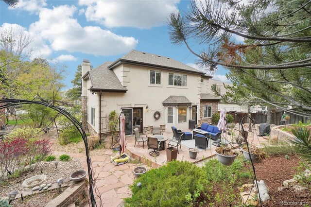 rear view of house with an outdoor living space, a chimney, a patio area, a shingled roof, and stucco siding