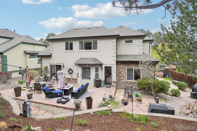 back of house with a patio area, a fenced backyard, roof with shingles, and stucco siding