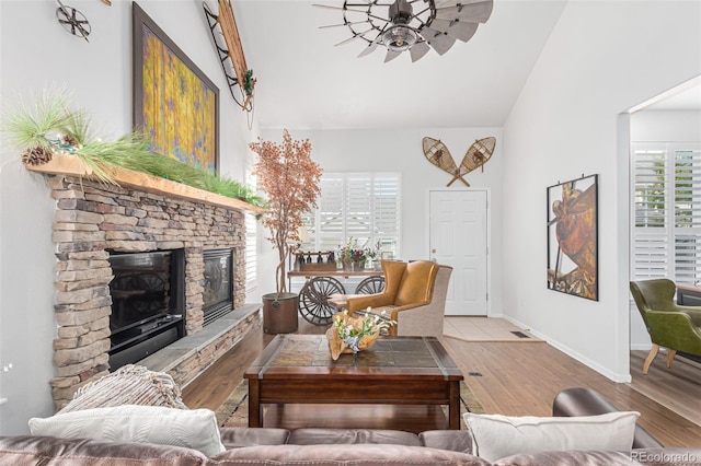 living room with a fireplace, vaulted ceiling, and light wood-type flooring