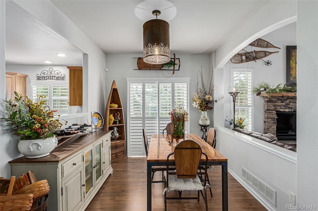 dining room featuring dark hardwood / wood-style floors and a stone fireplace