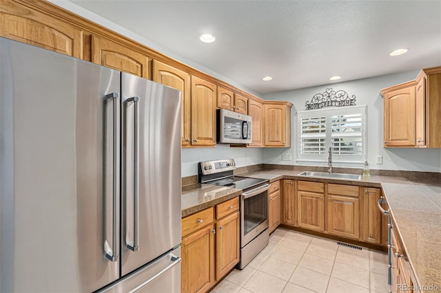 kitchen with appliances with stainless steel finishes, sink, and light tile patterned floors