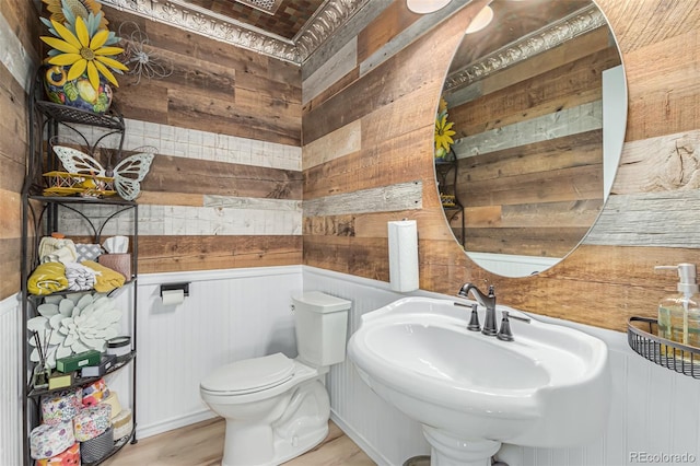 bathroom featuring hardwood / wood-style flooring, sink, wood walls, and toilet