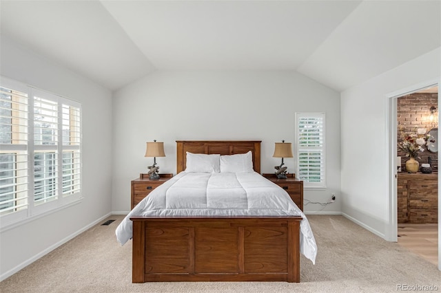 bedroom featuring light colored carpet, vaulted ceiling, and multiple windows