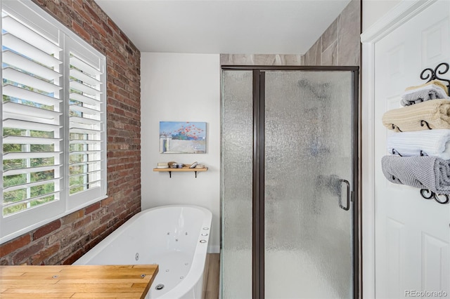 bathroom featuring brick wall and separate shower and tub