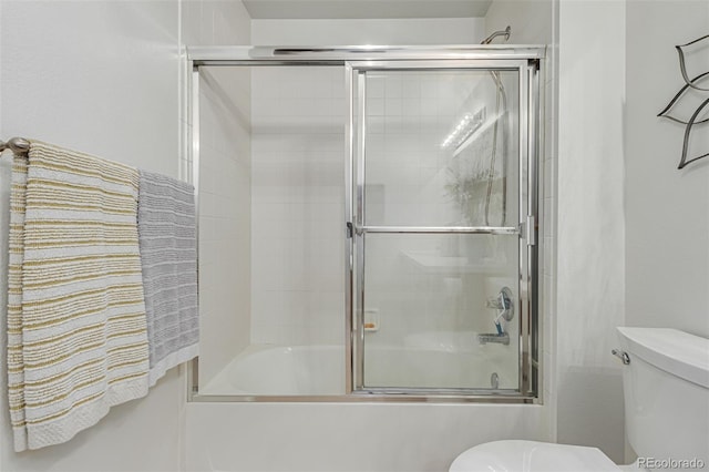 bathroom with combined bath / shower with glass door and toilet