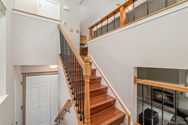 stairway featuring a high ceiling and a tile fireplace