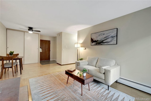 living room featuring light wood finished floors, a baseboard radiator, a ceiling fan, and baseboards