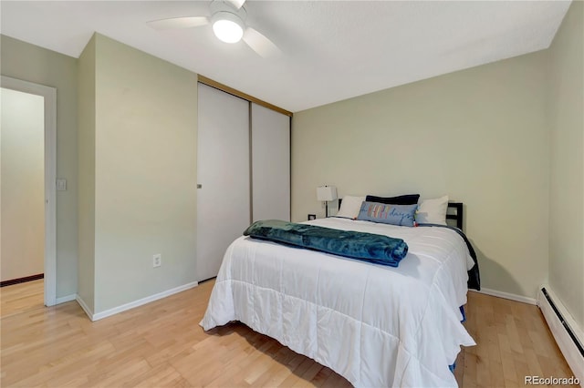 bedroom featuring light wood finished floors, a baseboard radiator, a closet, a ceiling fan, and baseboards