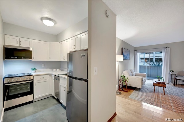 kitchen featuring white cabinets, light wood-style flooring, stainless steel appliances, a textured ceiling, and light countertops