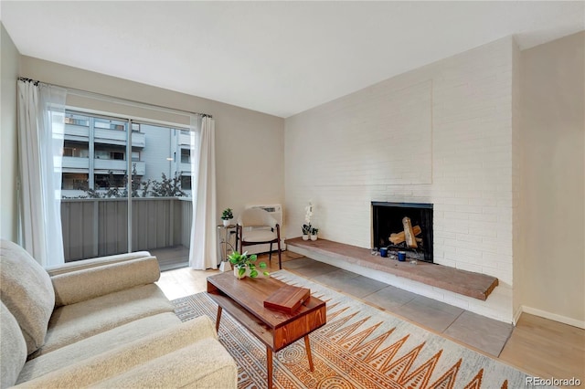 living area with baseboards, a brick fireplace, and wood finished floors