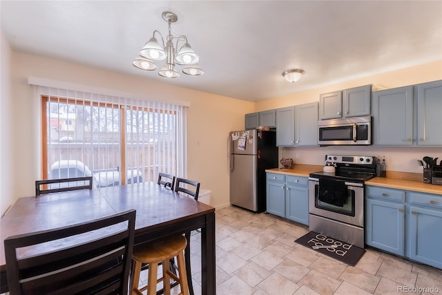 kitchen featuring pendant lighting, butcher block counters, stainless steel appliances, and a notable chandelier