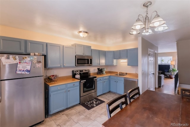 kitchen with stainless steel appliances, a chandelier, pendant lighting, and butcher block countertops