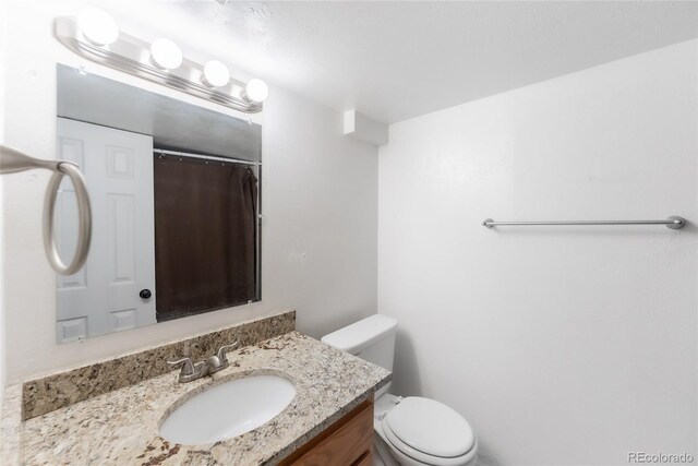 bathroom with curtained shower, toilet, and vanity