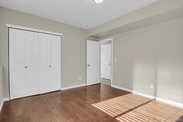 unfurnished bedroom featuring dark wood-type flooring and a closet