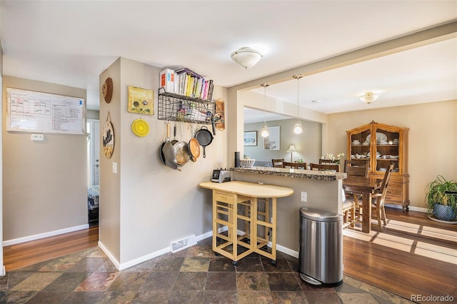 7780 S Kendall Blvd, Littleton, CO 80128 - kitchen featuring stone tile floors, a kitchen breakfast bar, hanging light fixtures, and a peninsula