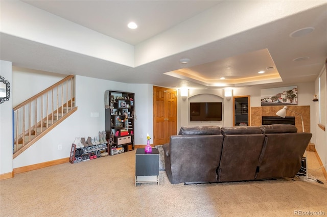 carpeted living room featuring a fireplace and a tray ceiling