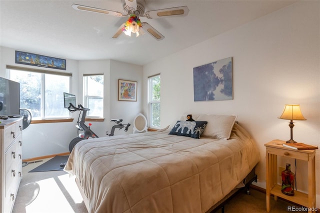 bedroom with ceiling fan, light colored carpet, and multiple windows