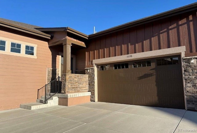 view of front of property with board and batten siding, stone siding, concrete driveway, and a garage