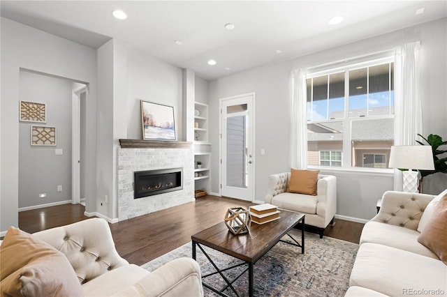 living area featuring built in shelves, recessed lighting, baseboards, and wood finished floors