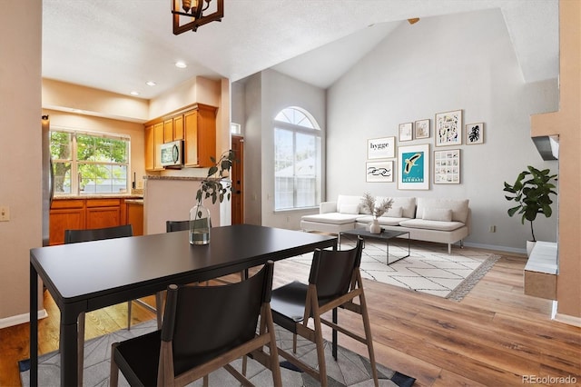 dining space with vaulted ceiling and light hardwood / wood-style flooring