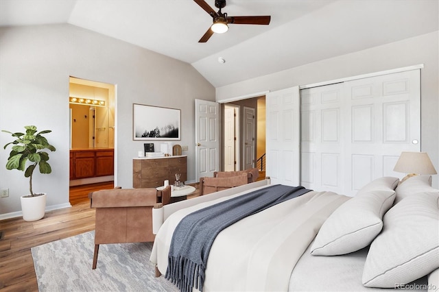 bedroom featuring ceiling fan, ensuite bathroom, wood-type flooring, vaulted ceiling, and a closet