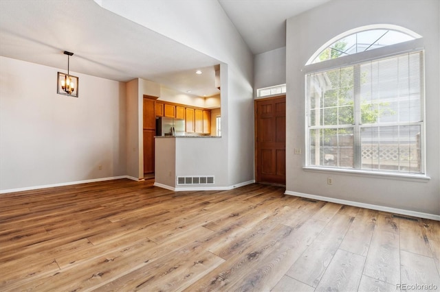 foyer entrance featuring light hardwood / wood-style floors, vaulted ceiling, and a notable chandelier