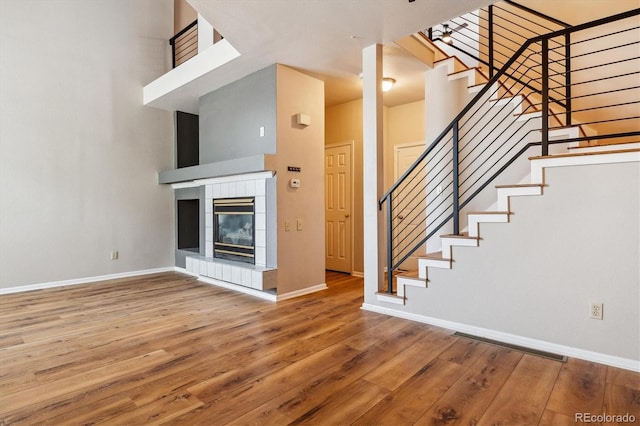 interior space featuring a tiled fireplace, hardwood / wood-style floors, and a high ceiling