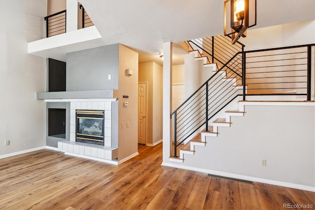 stairway with a tile fireplace and wood-type flooring